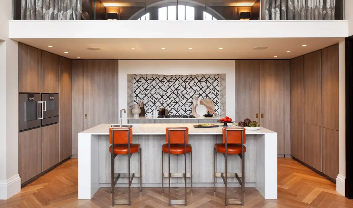Timber kitchen with white island and orange bar stools beneath an arched window, King's Library